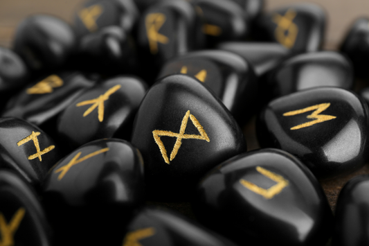 Close-up of glossy black rune stones etched with golden Norse symbols, evoking mysticism and sacred ritual practice.