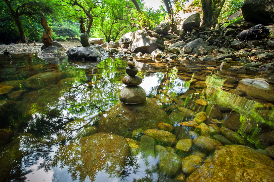 Zen stone stack balanced in a tranquil forest stream at sunrise, reflecting nature and mindfulness—symbol of morning rituals, inner peace, and Norse-inspired clarity