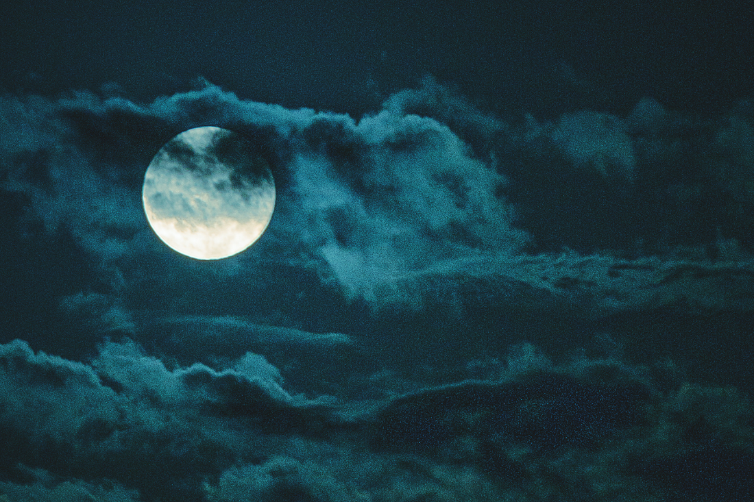 Full moon veiled by dark clouds in a night sky, evoking Norse mysticism and lunar ritual energy under the watch of Máni, the moon god.