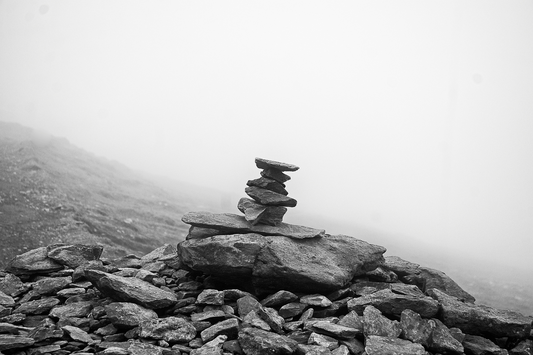 Solitary stone cairn rises from a misty mountain path, evoking Norse ritual, memory, and sacred stillness.